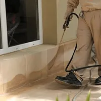 General pest control technician spraying exterior perimeter around a home in Newark, NJ