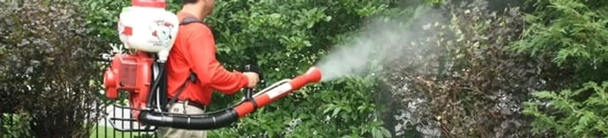 Mosquito control technician fogging shrubs and landscaping for mosquito treatment in Newark, NJ